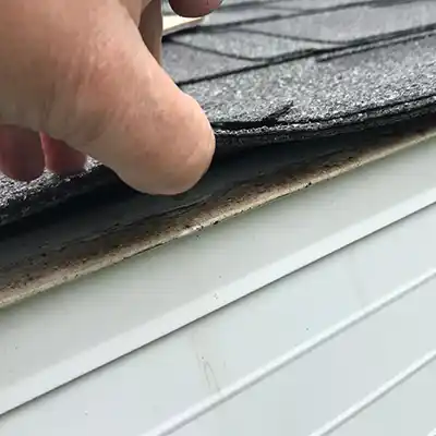 Roofer inspecting underneath a shingle