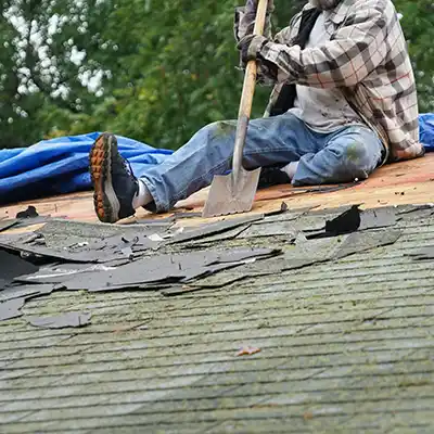 Roofer removing old, moldy shingles with a shovel